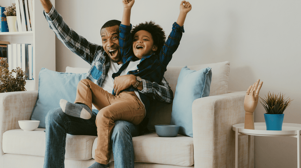 father and son celebrating a sporting event at home