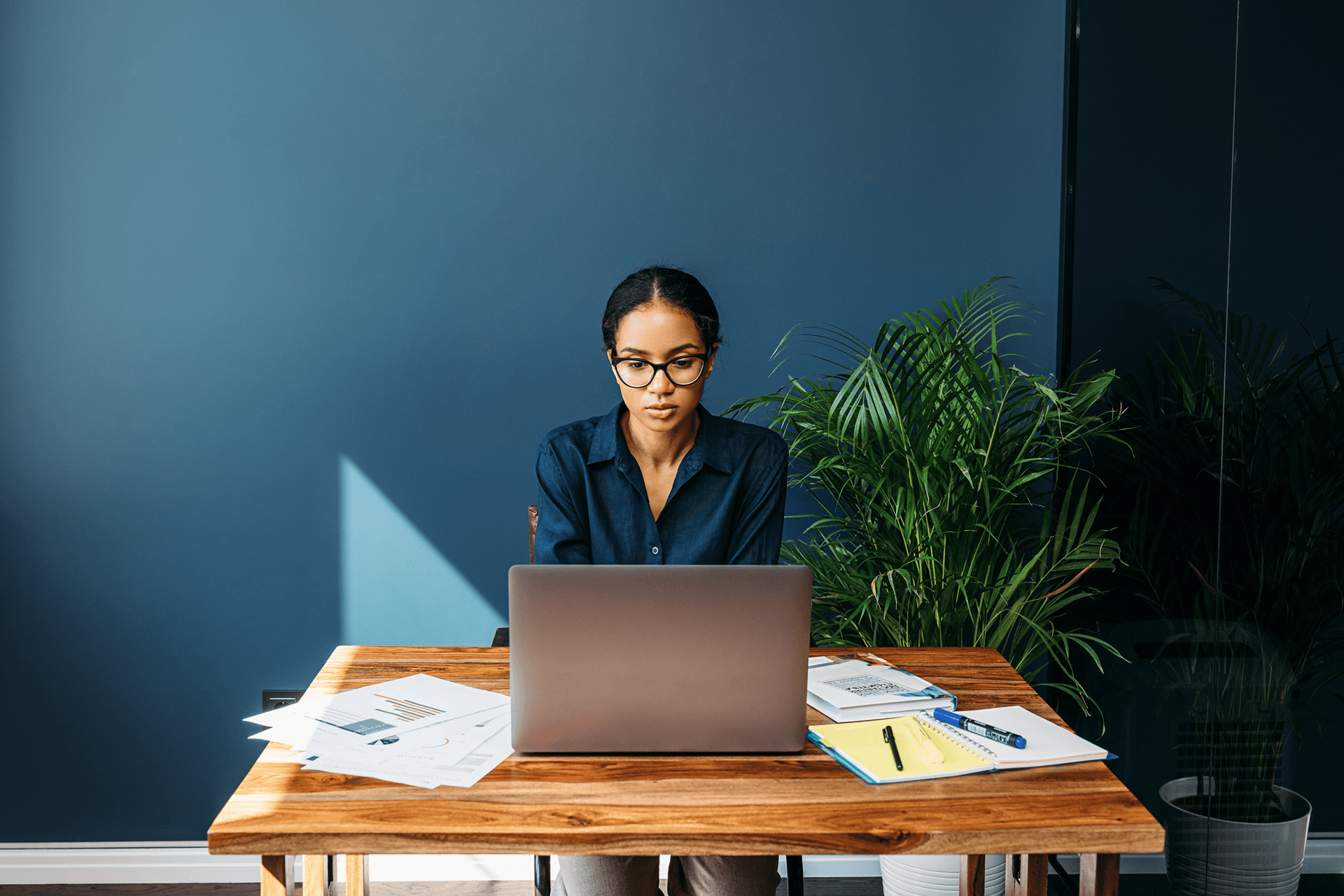Woman working on a laptop while sitting on a desk