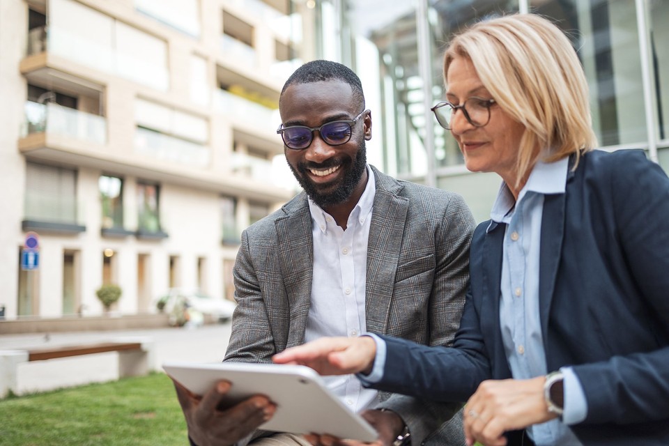 Man looking at ads with an ipad and a woman pointing at the ads next to him. 