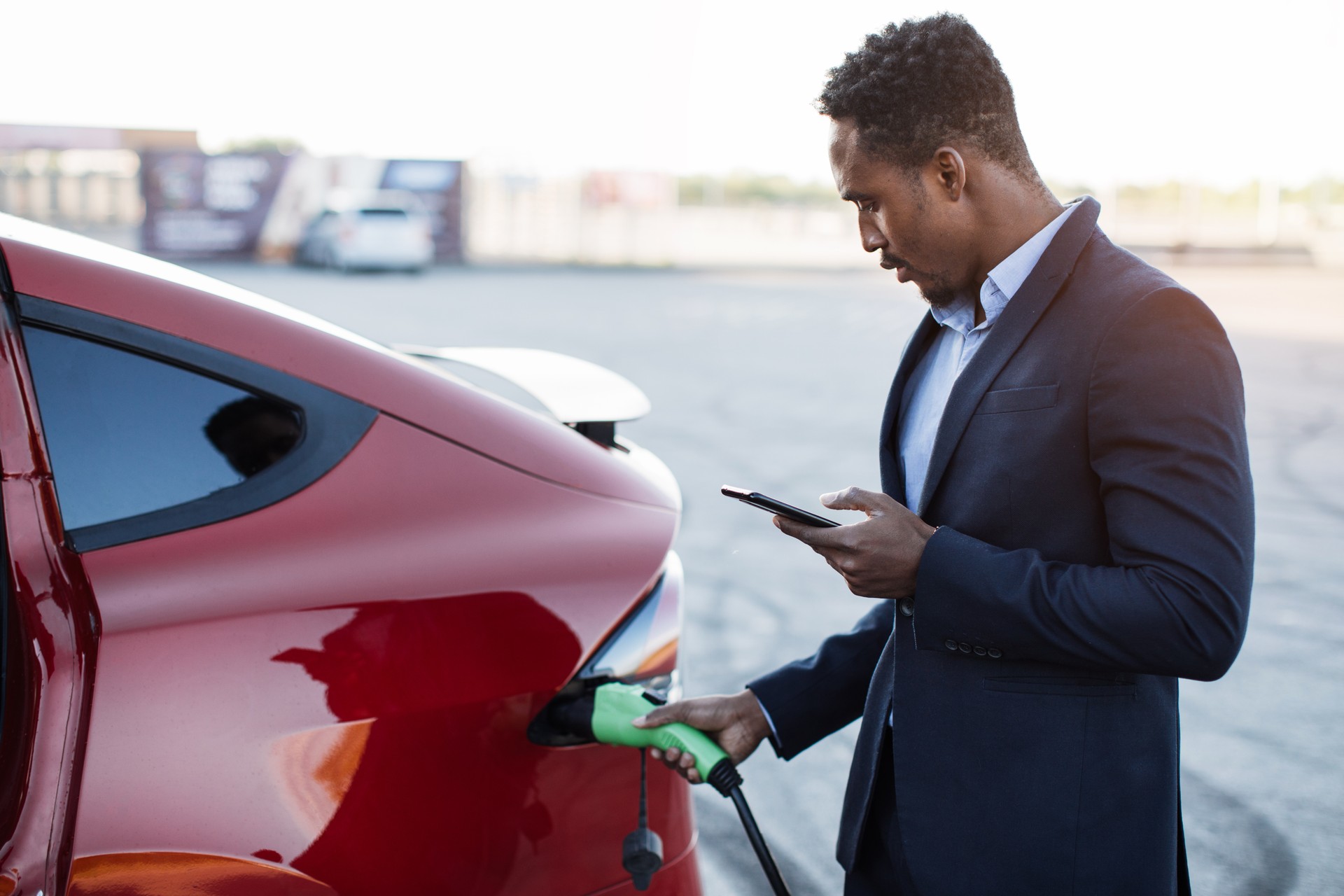 man plugging up charger to electric vehicle 