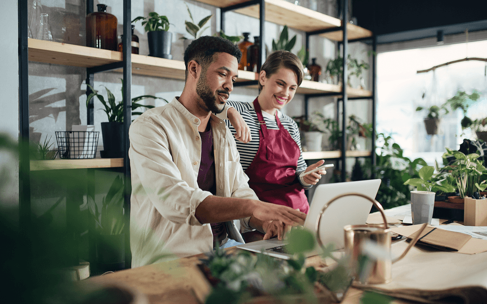 man and woman looking at laptop and mobile phone