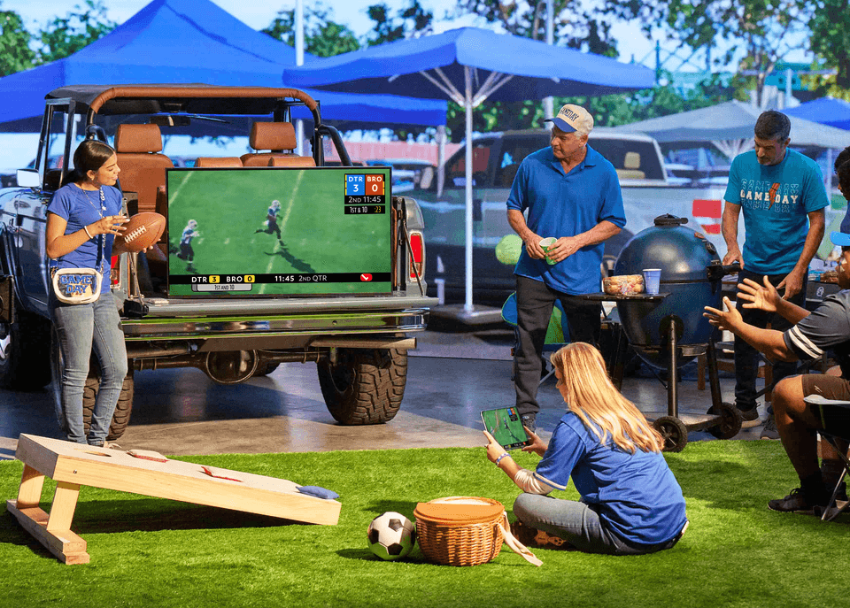 A group of people at a sport's party watching sports on different devices.