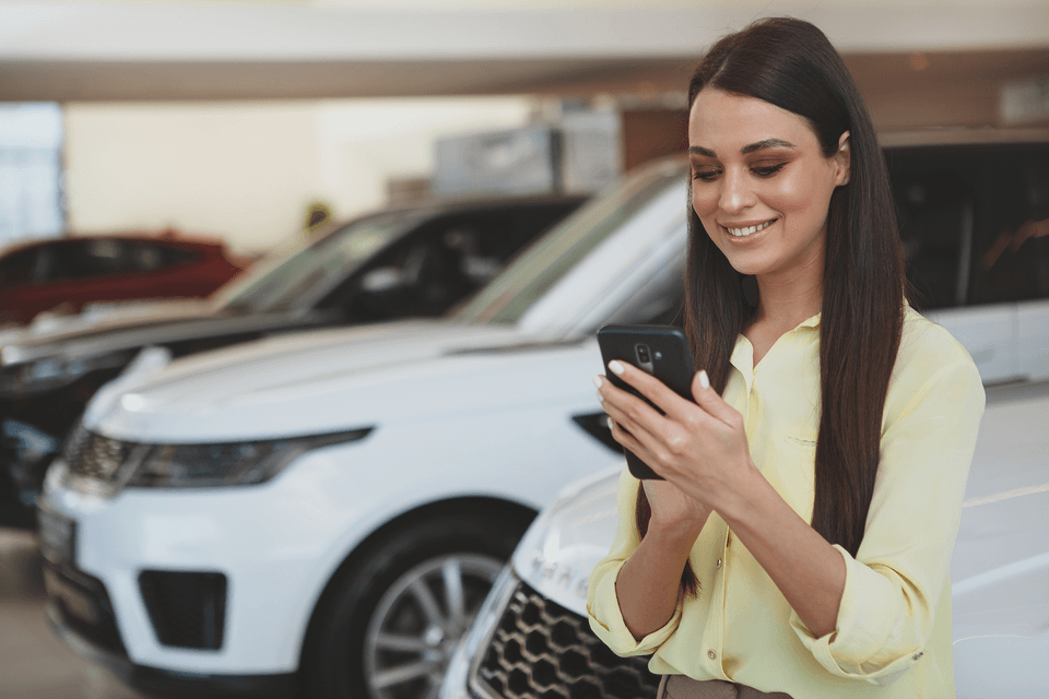 Women looking at cellphone in front of car lot